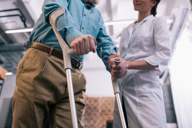 istock Old man leaning on crutches and female doctor hand 932836816