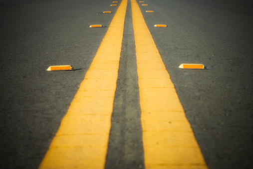 A close-up of a double yellow line on a road.