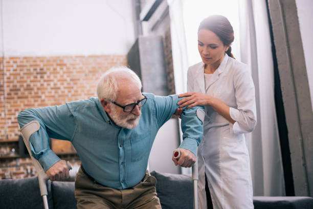 istock Doctor holding old male patient with crutches 932842450