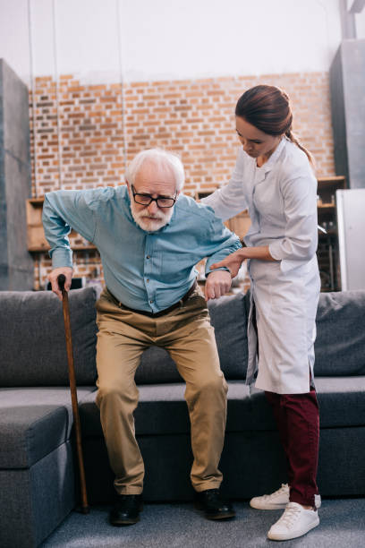 istock Doctor assisting male patient with cane 932845194