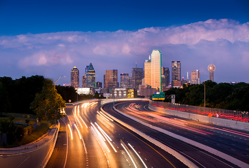 Long exposure of evening rush hour with cars racing in and out of Downtown Dallas, Texas on a stormy night.