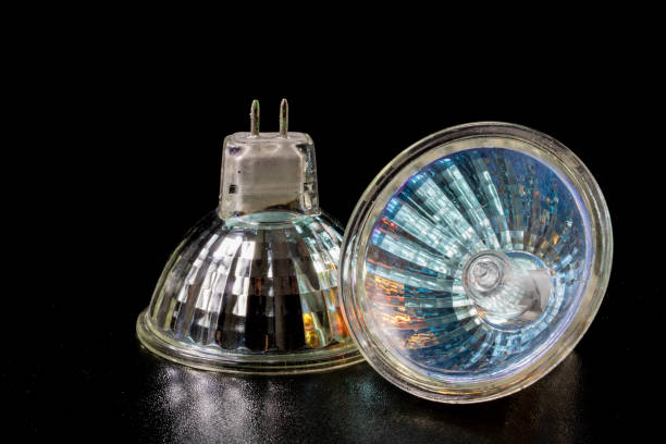 istock Halogen bulb in a reflective shade. Lighting accessories on a dark tole. Black background. 932922892
