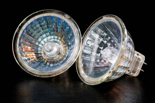 istock Halogen bulb in a reflective shade. Lighting accessories on a dark tole. Black background. 932929142