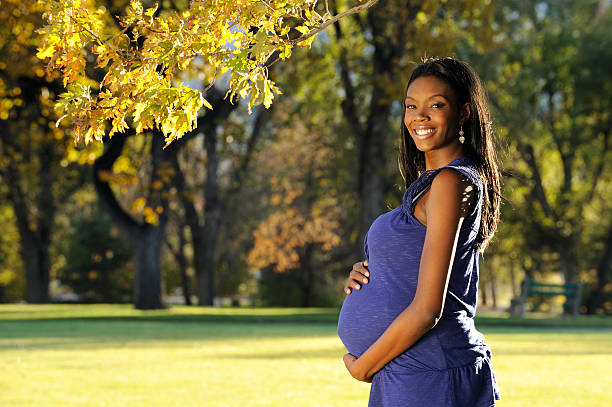 Young smiling pregnant African American lady in a park stock photo