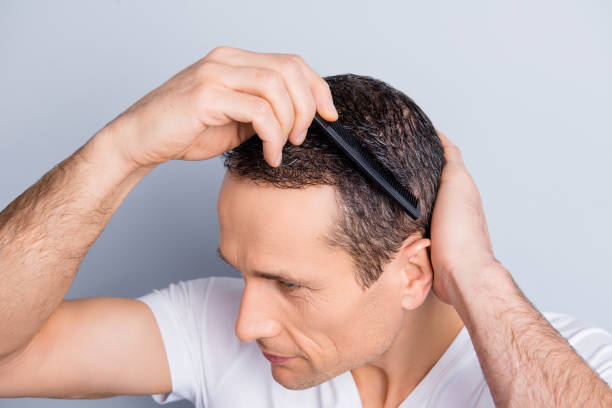 istock Top view close up portrait of brunet, stylish, neat, experienced man combing, fixing, correcting his hair with hairbrush, isolated on grey background 932956310