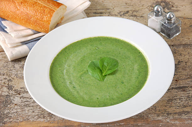 An elegant bowl of cream of spinach soup served on a rustic wooden table.  (This could also be cream of broccoli, watercress soup, or any other soup of blended green vegetables.)