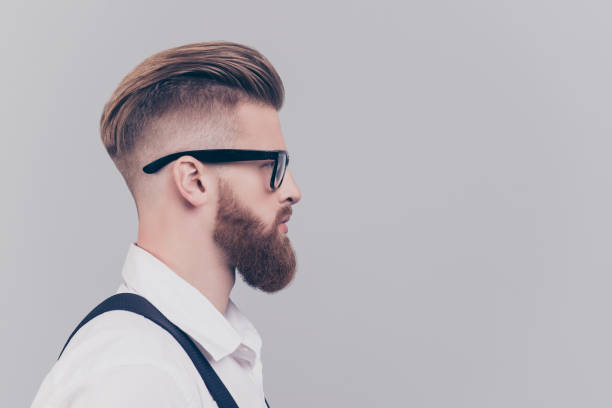 istock Profile half-faced side view portrait of serious confident concentrated attractive manager with blonde hair wearing rimmed glasses white shirt black suspenders isolated on gray background empty blank 933004476