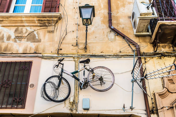 Bicycle hanging next to a television antenna on the wall of the facade of an old building in the old town of Palermo in Sicily, Italy