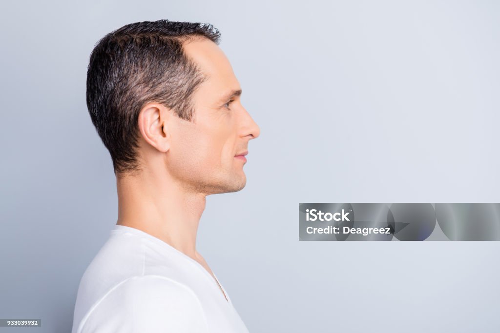 Profile, half face portrait with copy space of trendy, attractive, stylish, man looking at empty place for advertisement, product, having perfect ideal oiled, dry skin, isolated on grey background Human Face Stock Photo