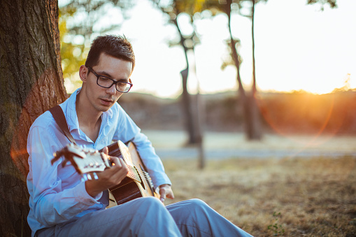 Young man playing acoustic guitar in nature