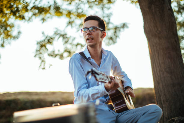 Young man playing acoustic guitar in nature