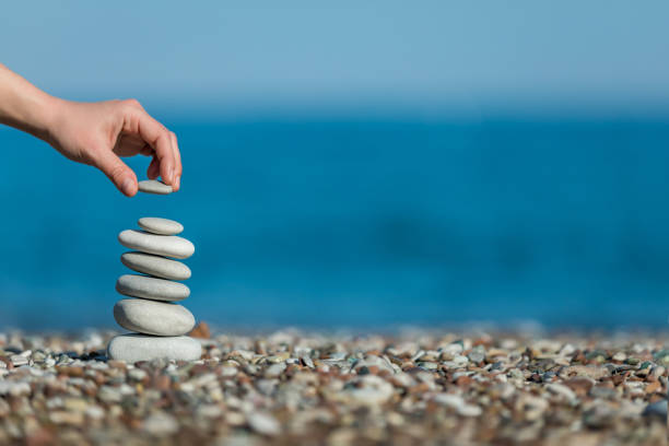 oman's hand balancing stacking stones on a beach - aspirations pebble balance stack imagens e fotografias de stock