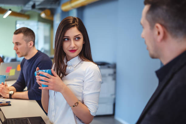 Girl looking at her colleague with love in her eyes Girl looking at her colleague with love in her eyes while he is talking flirty stock pictures, royalty-free photos & images