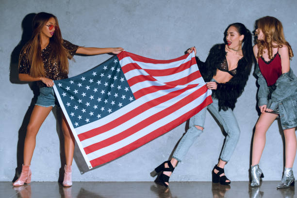 istock multicultural young women with american flag against concrete wall 933112632