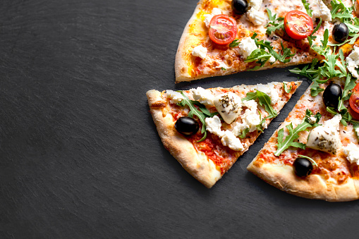 Sliced hot pizza with seafood, cheese and herbs  on black background for lunch or dinner crust. Pizza menu.