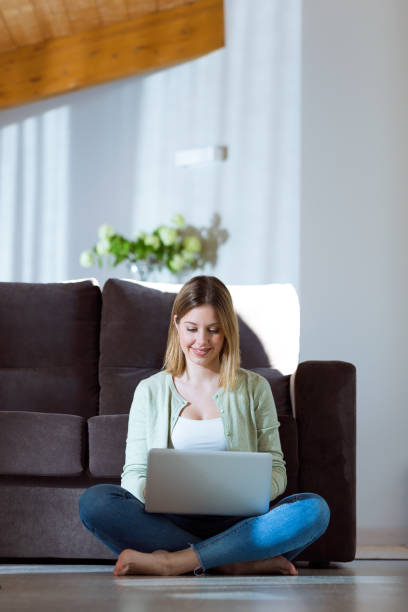istock Beautiful young woman using her laptop at home. 933120548