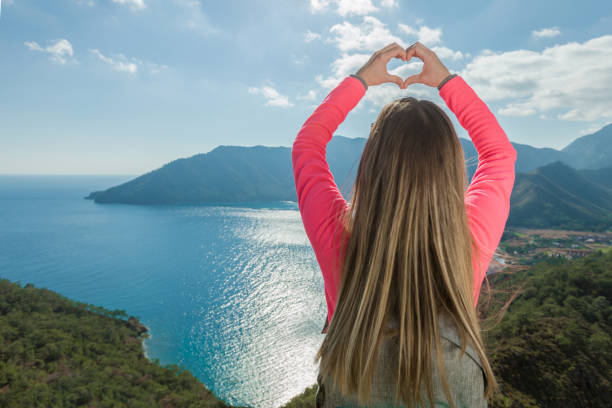 istock Young woman on mountain makes heart shape finger frame 933129562