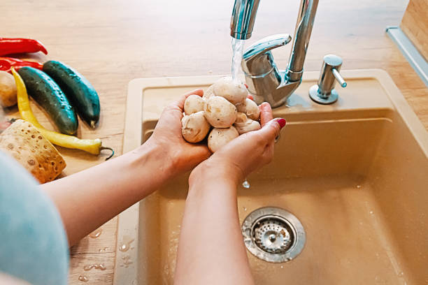 Women's hands wash mushrooms in a modern kitchen interior, healthy food concept. Selective focus. Vegetarian healthy food. Hands woman washing vegetables