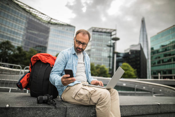 istock Mature businessman texting and using lap top in London 933130510