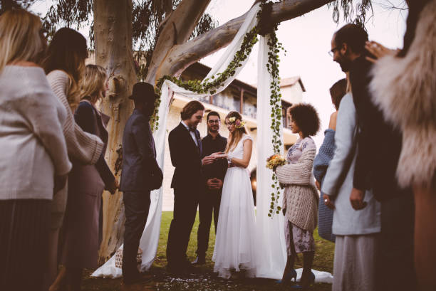 istock Bride and groom exchanging wedding rings at ceremony with guests 933132928