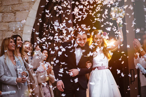 feliz novia y el novio saliendo de la iglesia y celebración - flower toss fotografías e imágenes de stock