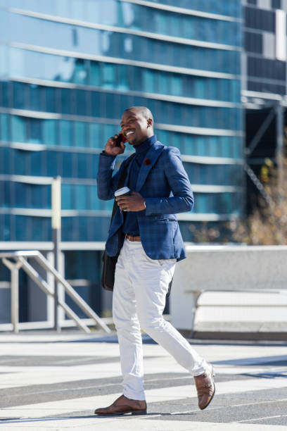 istock Handsome businessman walking through the city while talking on his mobile phone. 933137032