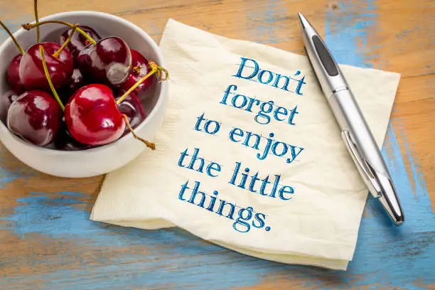 Do not forget to enjoy the little things - handwriting on a napkin with a bowl of cherries