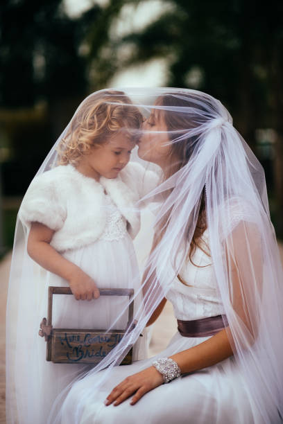 junge braut umarmen und küssen kleine blumenmädchen bei hochzeit - veil bride lace married stock-fotos und bilder