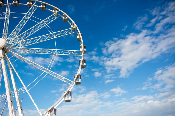 istock Horizontal View of a White Ferris Wheel on Partially Cloudy Sky Background 933137806