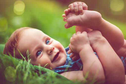 Cute Baby Playing With His Legs On The Grass Stock Photo - Download Image  Now - Baby - Human Age, Nature, Foot - iStock