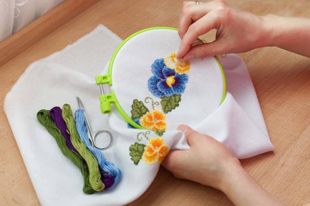 female hands are embroidering flowers on the canvas. cross stitch technique. - embroidery seam shirt sewing imagens e fotografias de stock