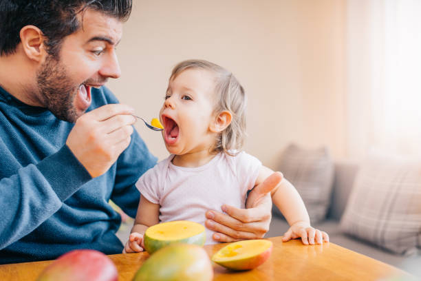 istock Father feeding toddler with spoon on table 933166842
