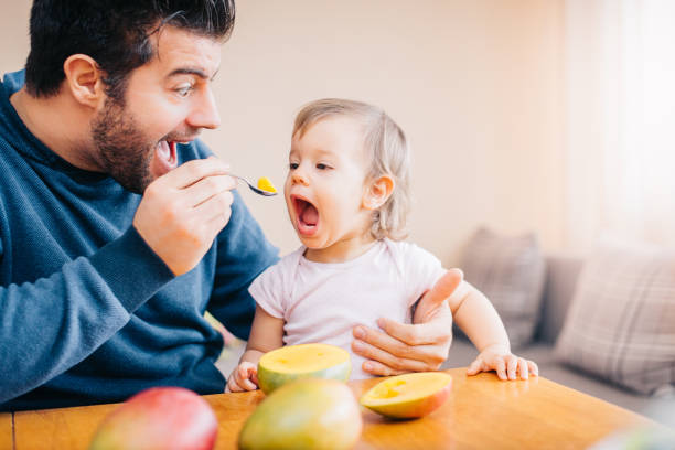 istock Father feeding toddler with spoon on table 933166862