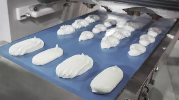 Cooking many sweet white meringue on blue production line. sweet food concept.