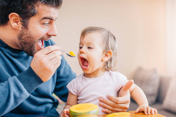 istock Father feeding toddler with spoon on table 933166882