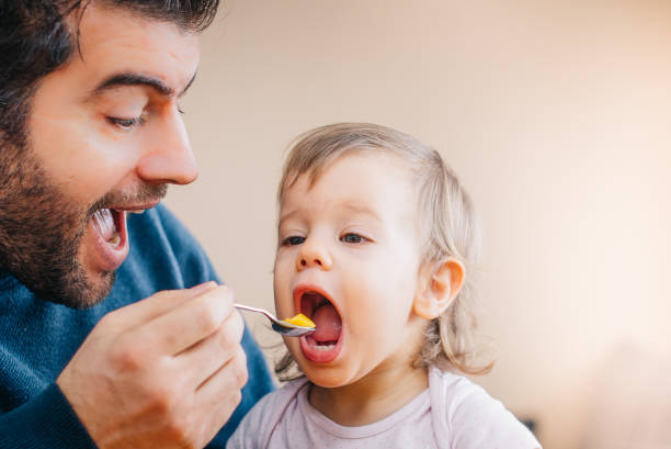 istock Father feeding toddler with spoon on table 933166892