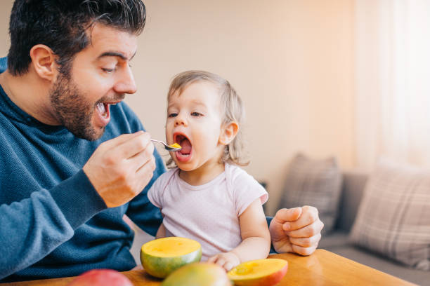 istock Father feeding toddler with spoon on table 933166948