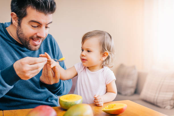 istock Father feeding toddler with spoon on table 933166956