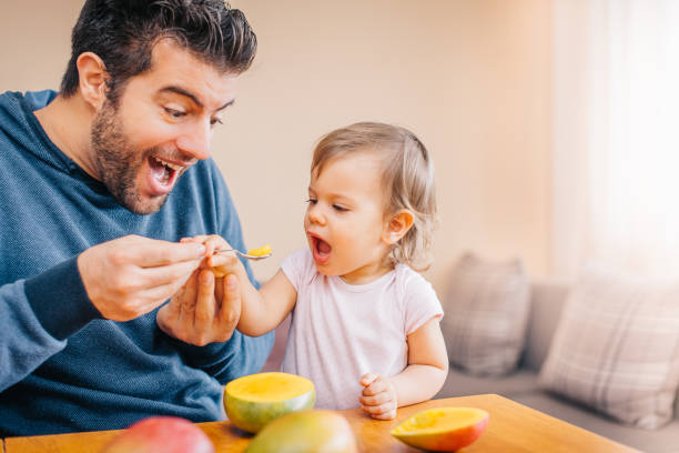 istock Father feeding toddler with spoon on table 933166996
