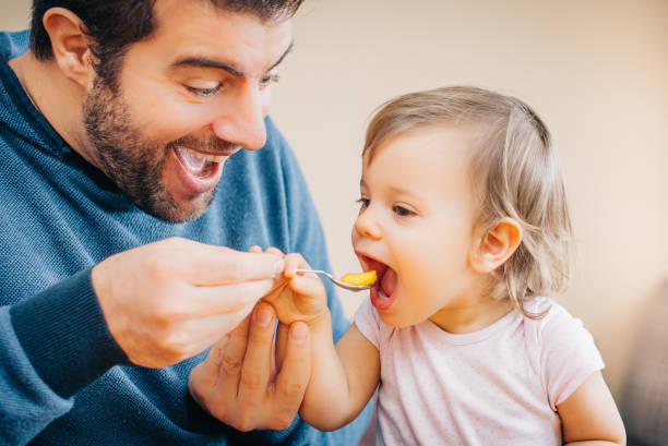 istock Father feeding toddler baby infant with spoon and mango 933166998