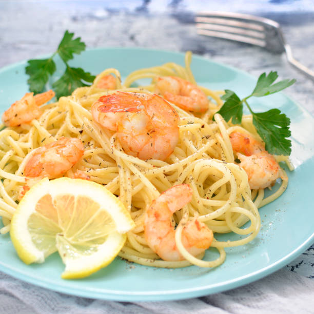 istock A delicious dinner, decorated with parsley and lemon. Spaghetti with shrimps on blue plates. Appetizing dish. 933167008