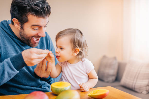 istock Father feeding toddler with spoon on table 933167034