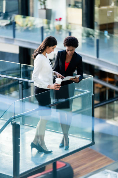 istock Two young female colleagues standing and discussing work 933175268