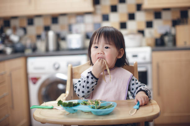 istock Baby girl eating messy at home kitchen 933175822