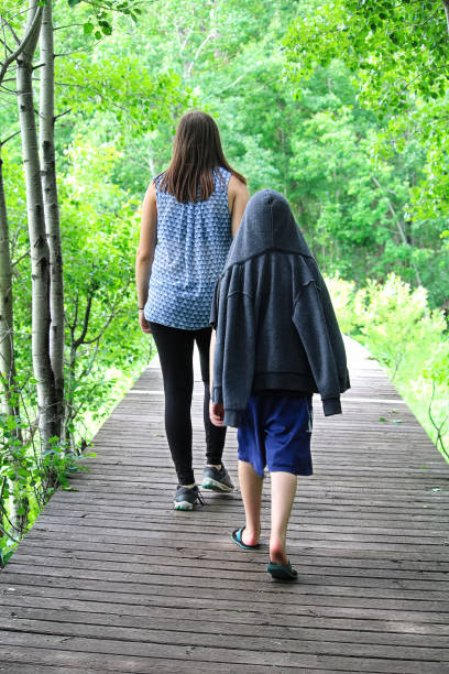 A young boy following a girl on a boardwalk on a tail