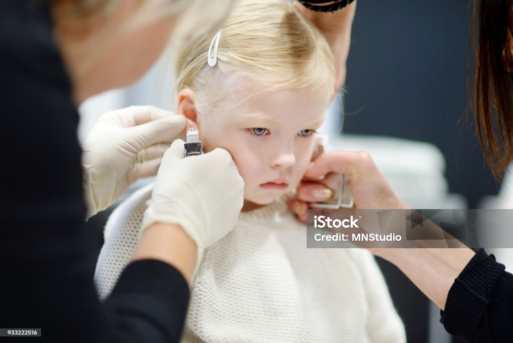 Adorable petite fille ayant ses oreilles percées - Photo de Crever libre de droits