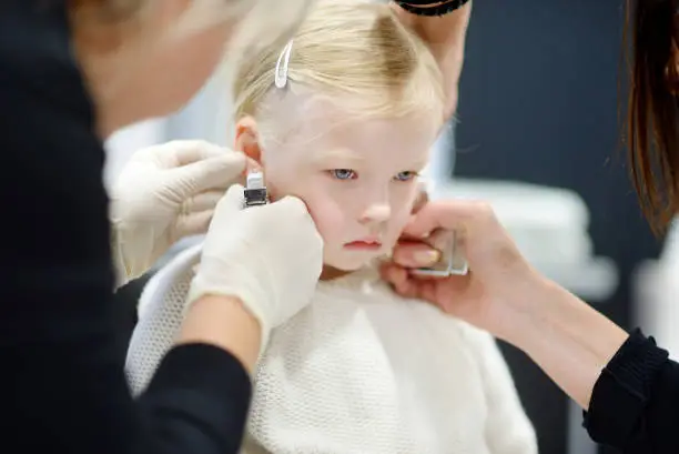 Photo of Adorable little girl having her ears pierced