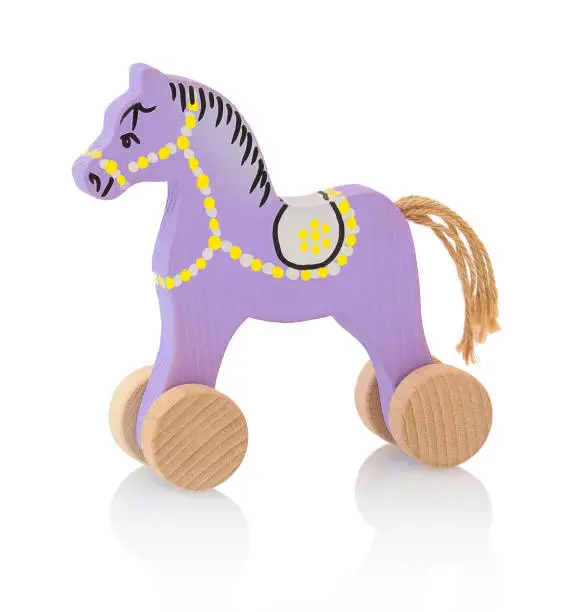 Children's small wheeled wooden horse isolated on the white background with shadow reflection. Small childish wooden pinky toy in the shape of horse on white background. Wooden handmade toy.