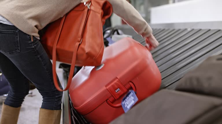 Woman picking up her travel bag from the baggage carousel at the airport