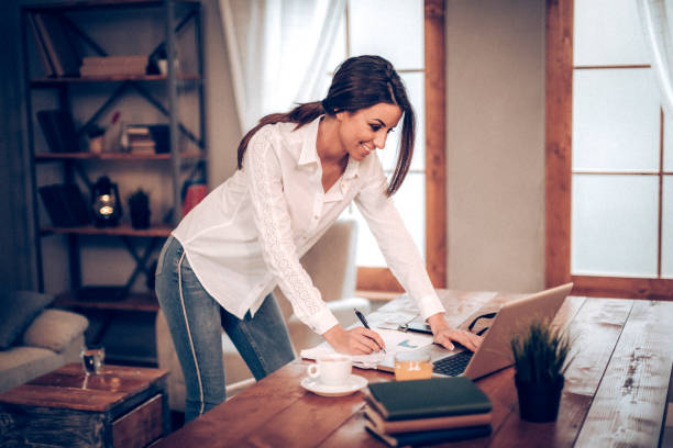 istock Woman standing in front of desk and using laptop 933268902